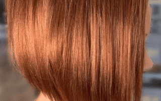 Close-up of a person's shiny, copper-toned hair styled in a sleek, straight bob, highlighting the strands' smooth texture and vibrant color.