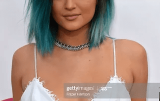 A young woman with black and teal ombre hair, wearing a white top and a choker, posing on the red carpet at the billboard awards 2014.