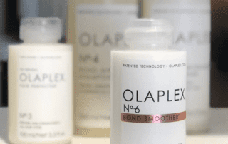 A selection of olaplex hair care products on a shelf, focusing on a bottle of no. 6 bond smoother in the foreground with other products blurred in the background.