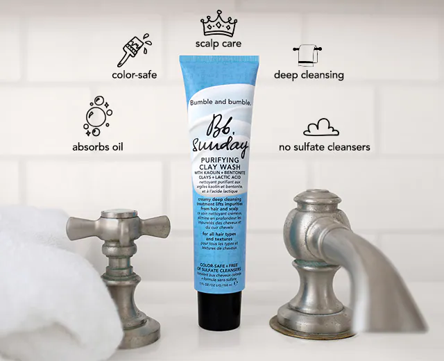 Product tube of bumble and bumble bb. sunday shampoo between two metal faucet handles on a bathroom counter, with highlighted features like color-safe and deep cleansing.