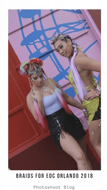 Two women posing at edc orlando 2018, styled in vibrant festival fashion with colorful braids, wearing eclectic accessories and sunglasses against a pink and blue backdrop.