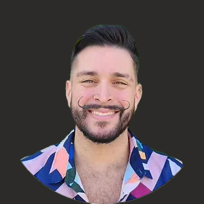 A smiling man with a trimmed beard and stylized mustache, wearing a colorful patterned shirt. the background is removed, showing just the man’s portrait in a circular frame.